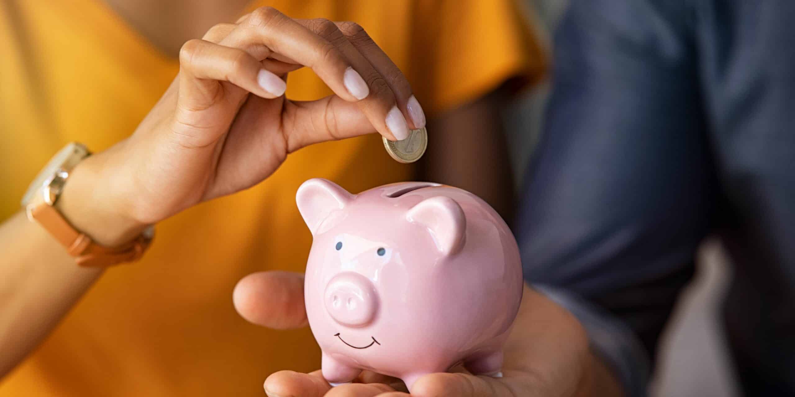 Man holding a piggy bank and a woman about to insert a coin